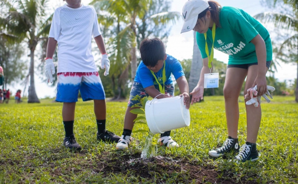 A Department of Land and Natural Resources (DLNR) staff member shows campers how to properly plant a tree at Taga Beach.