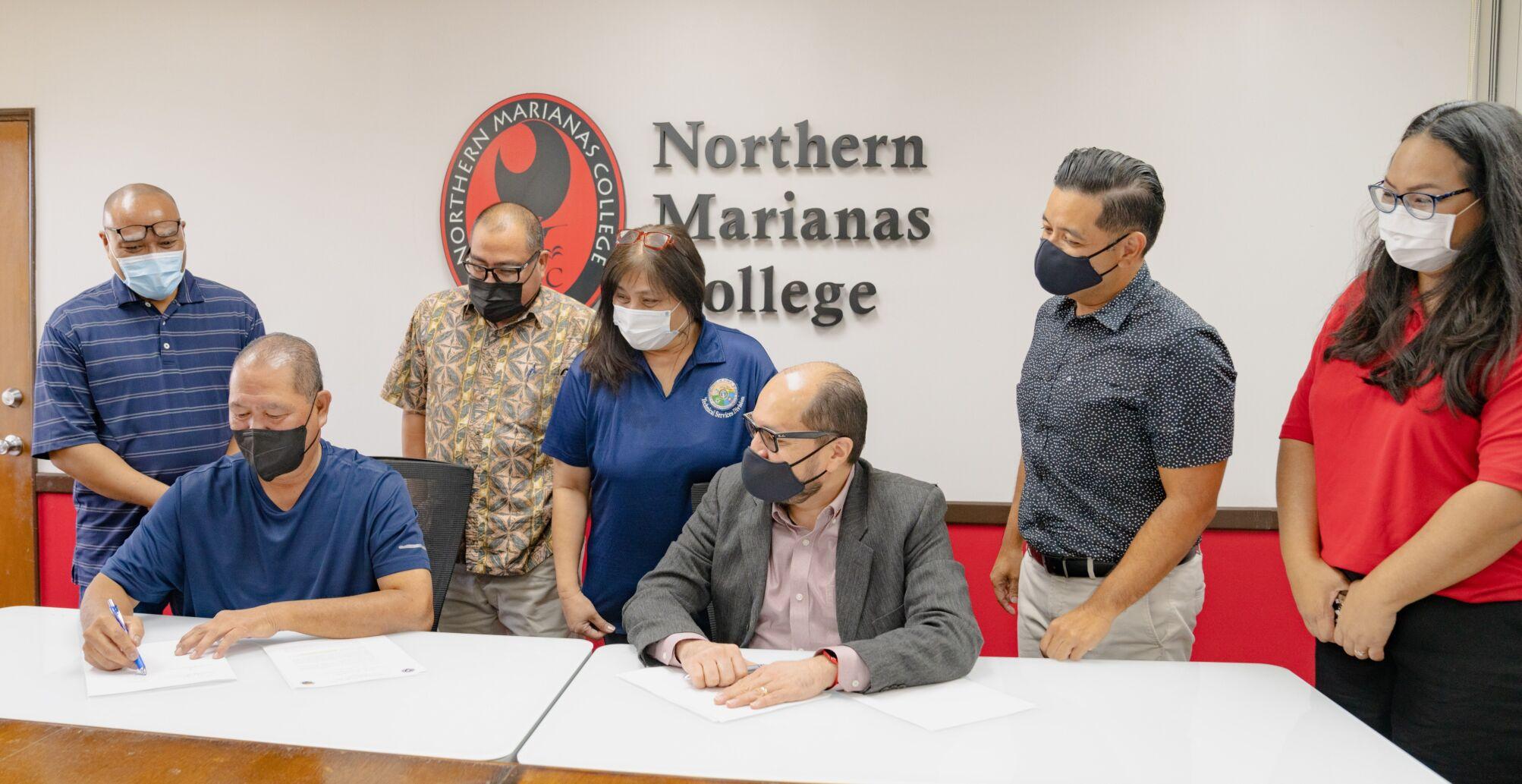 Northern Marianas College has signed an agreement with the Department of Public Works to establish a federally funded on-the-job training and social support program.  In the picture are Department of Public Works Secretary James Ada, second left, signing the MOA as NMC President Galvin S. Deleon Guerrero, Vice President for Administration and Advancement Frankie Eliptico, second right, DPW and NMC staff look on Tuesday in the NMC administration conference room.
