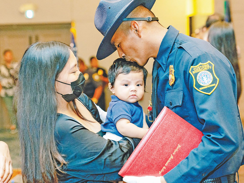 Customs and Biosecurity graduate Kane P. Ybanez plants a kiss on his son’s head after receiving his badge during the Division of Customs and Biosecurity 9th Cycle Academy graduation yesterday, July 25, 2022, at the Saipan World Resort’s Royal Taga Ballroom. The academy was coordinated in partnership with Northern Marianas College. Ybanez, who received a leadership recognition award during the ceremony, joins 28 other Customs and Biosecurity graduates. (NMC)