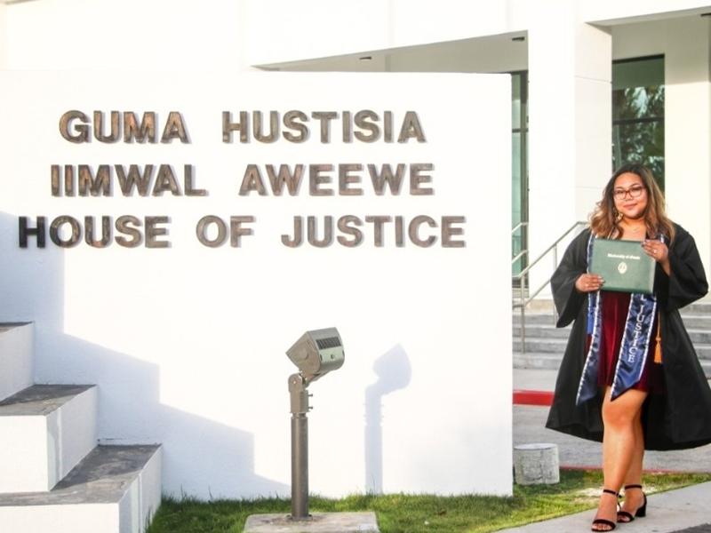 Graduate Josephine Estrada holds her University of Guam diploma in front of the CNMI Judicial Building in Susupe, Saipan where she works.