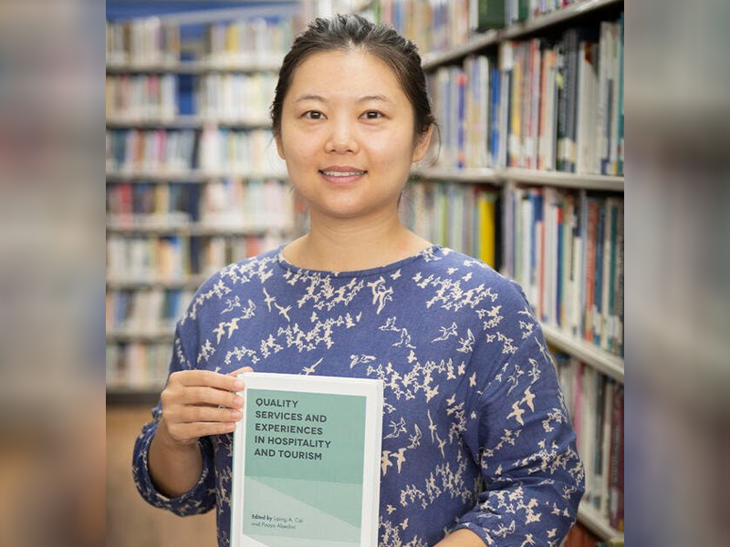 Dr. Yunzi Zhang with a book she contributed to. The chapter she wrote, “Quality Experiences of China's Family Tourists in the United States,” was recognized as an Outstanding Author Contribution in the 2019 Emerald Literati Awards.