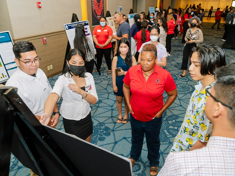 Northern Marianas College students Dimitri Sablan, Ashanti Peredo, Xue Qiu, Darlyn Ubarra, and Kiran Shrestha present their findings to audience members during NMC's 2nd Annual Research Symposium held at the Saipan World Resort on April 29, 2022